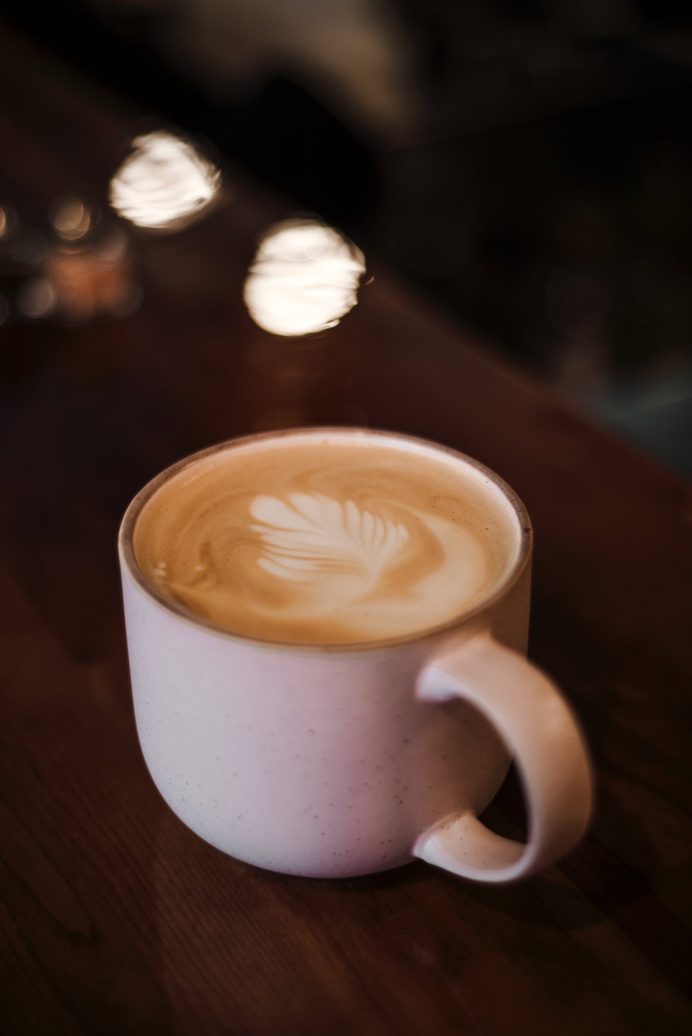Un latte avec sa rosetta, sur une table de bois