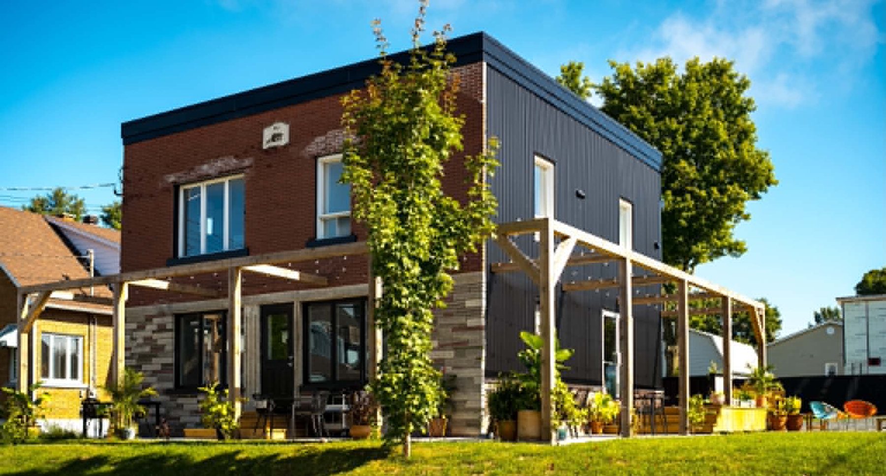 La devanture du Tingz Café : brique, revêtement noir et pergola de bois